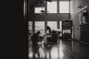 Black and white interior photograph showing sunlit room with hardwood floors and tall windows.