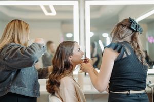 Stylists work on preparing someone for a special event in a bright salon setting.