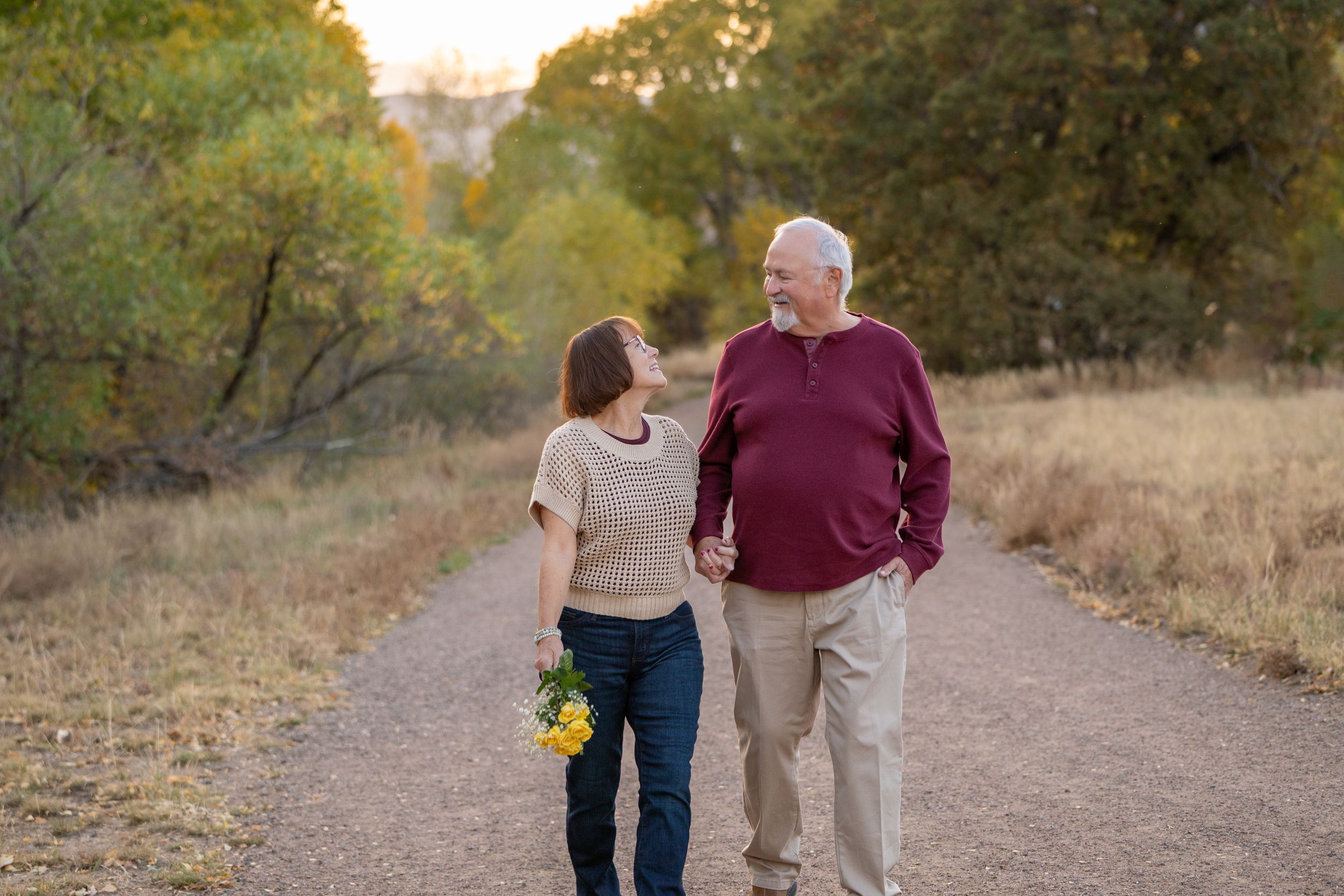 Couple walking together on dirt path during golden hour.