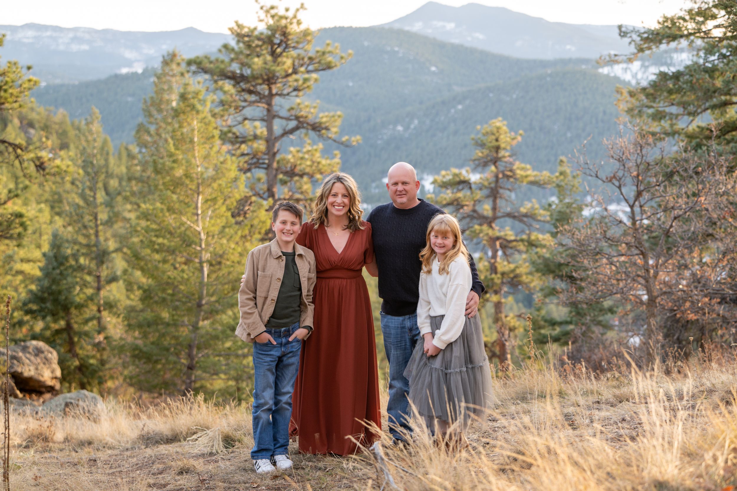Family portrait with mountain backdrop featuring coordinated fall outfits.