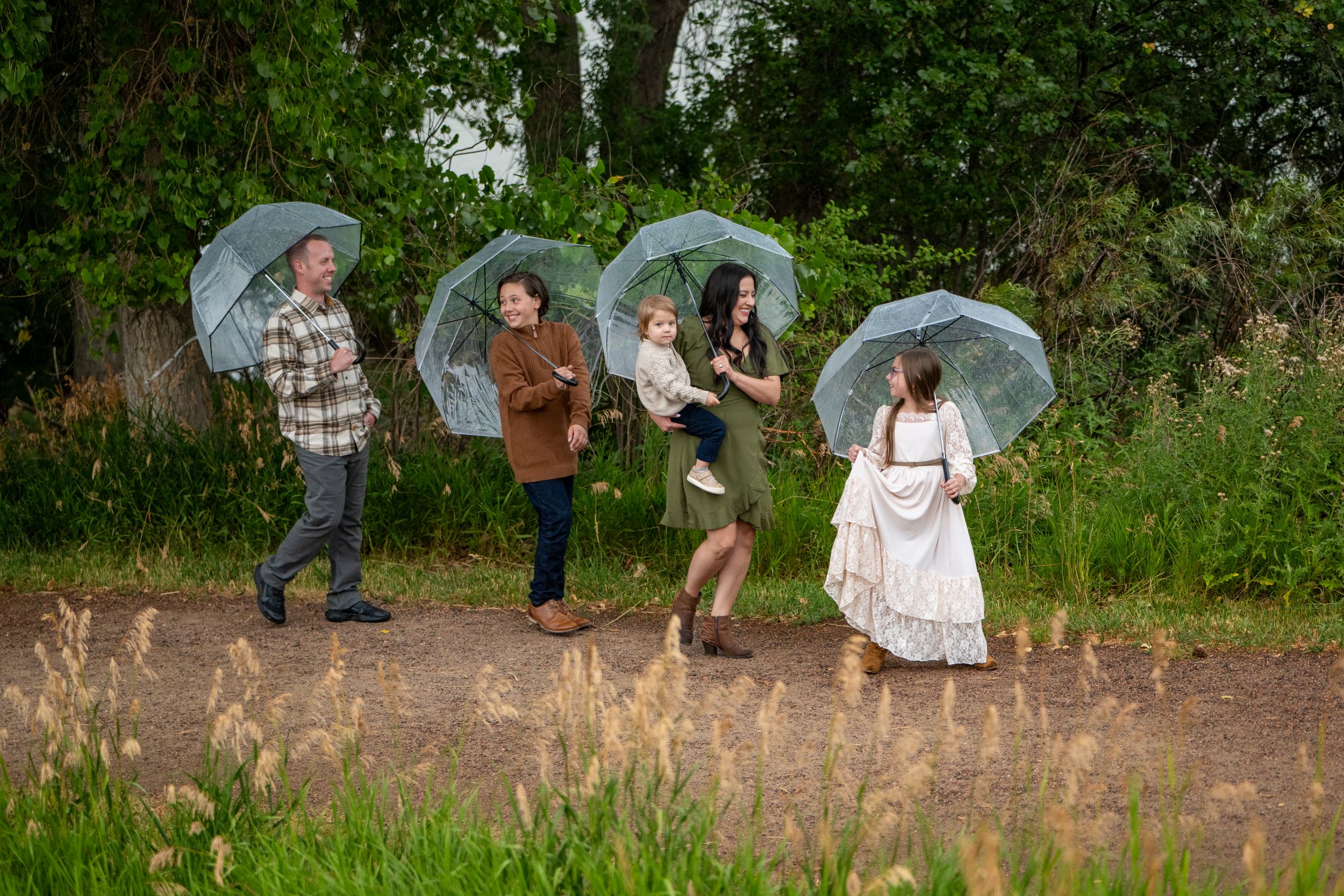 A group walking on stone stairs with umbrellas and formal attire at an outdoor event in a garden setting.