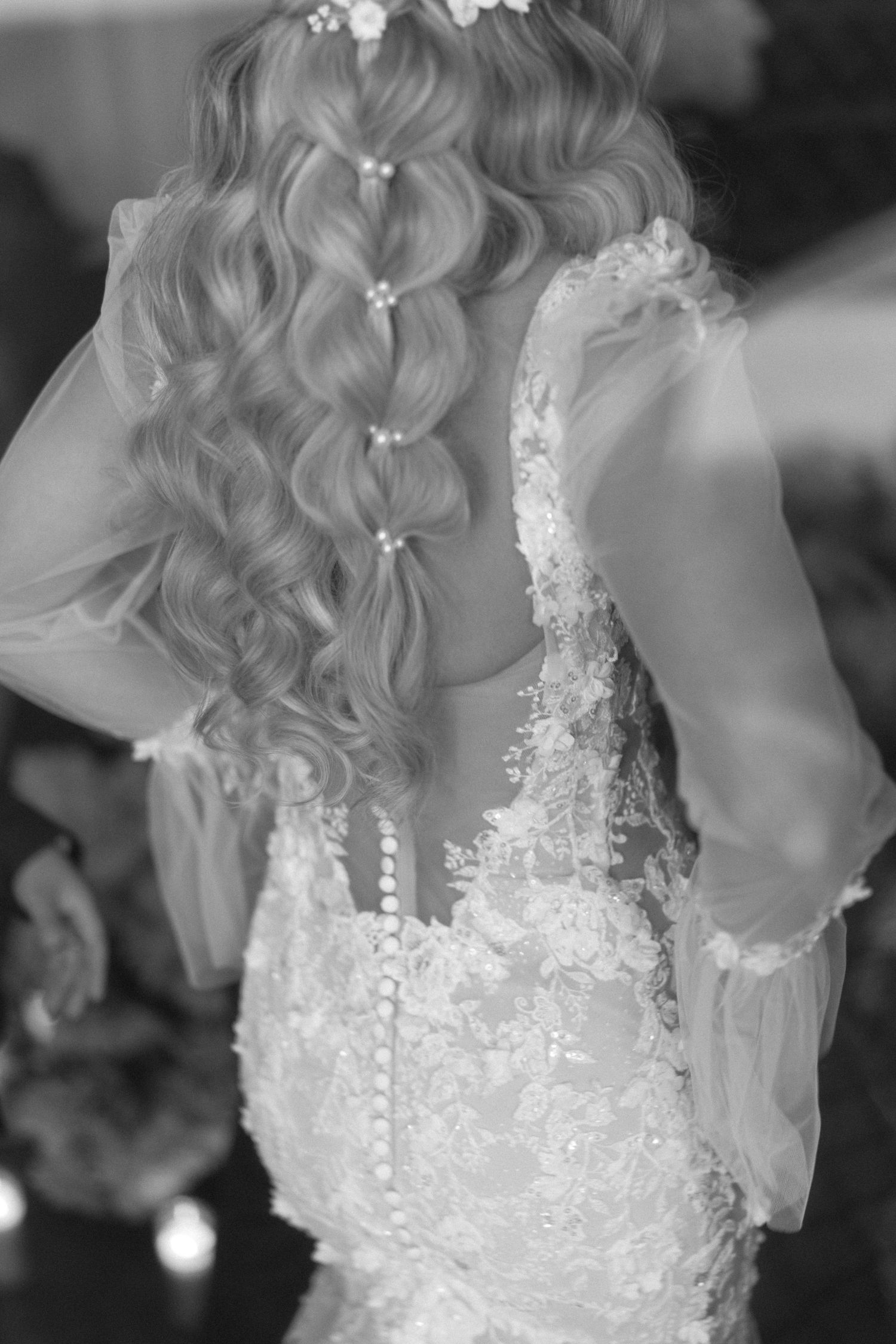 Black and white photo of bride and groom holding hands walking together on their wedding day.