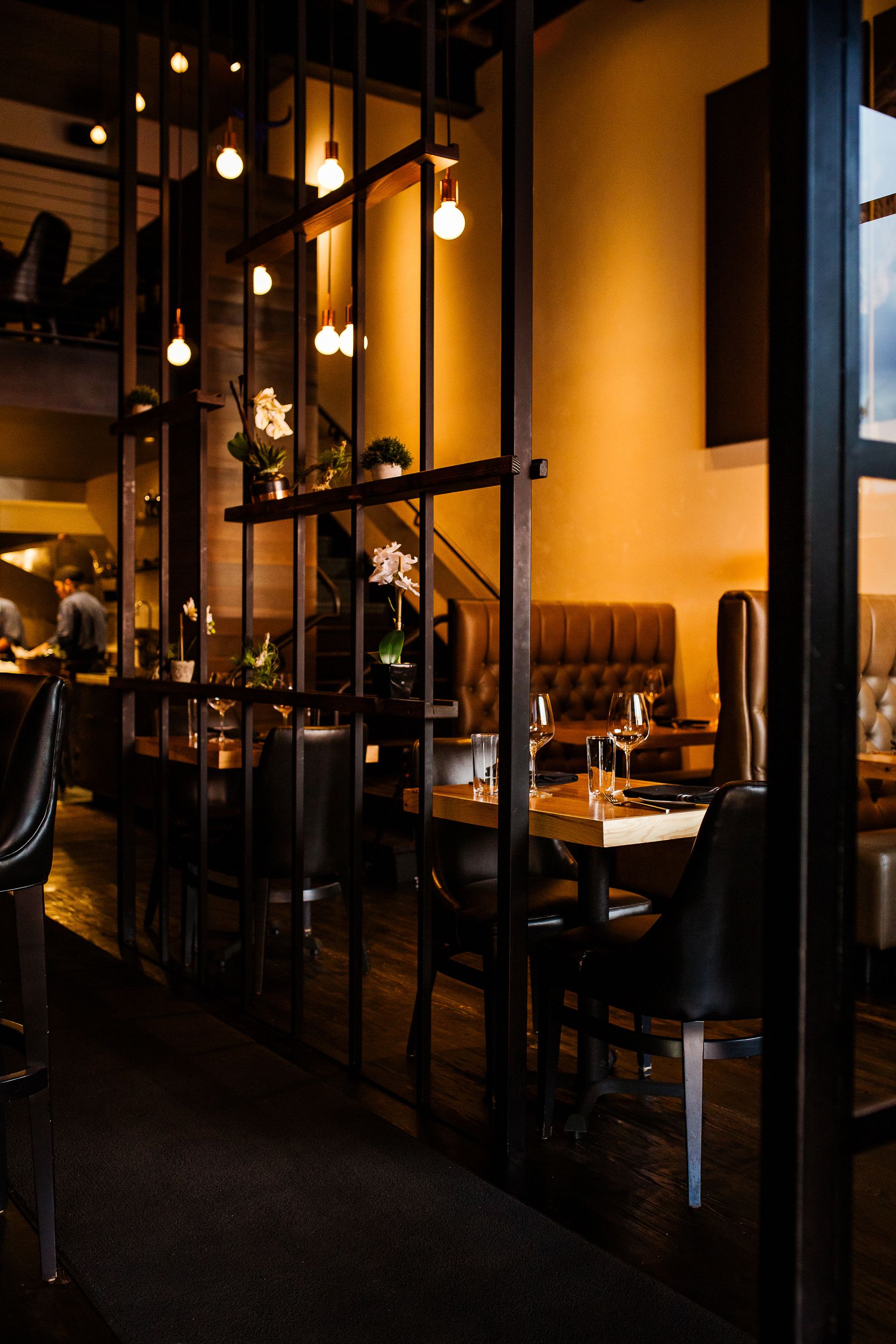 Moody restaurant interior with hanging pendant lights and leather booth seating.