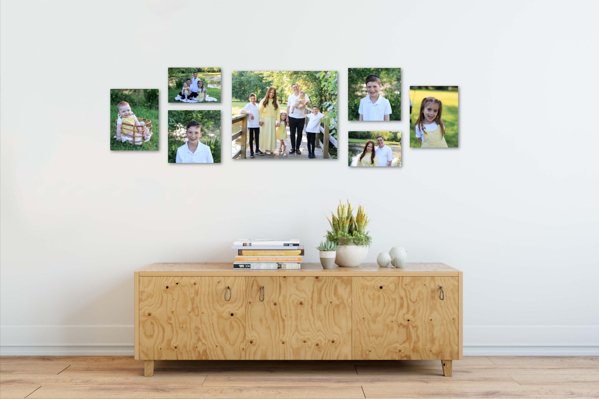Modern wooden media console with decorative photos displayed on top against white wall in minimalist living room.