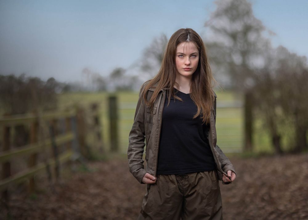 Fashion portrait of teenage girl in earth tone outfit standing in countryside field for editorial shoot