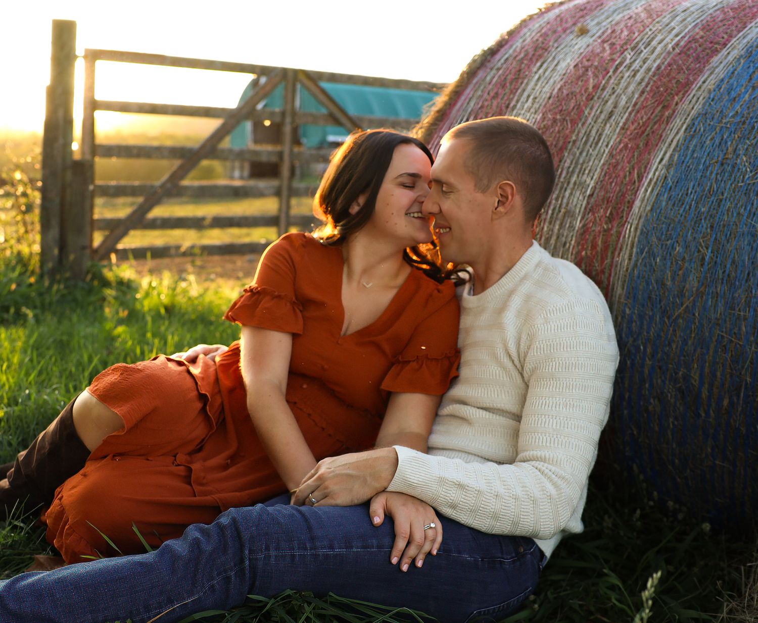 Couple embracing in a golden field during sunset wearing plaid and black.