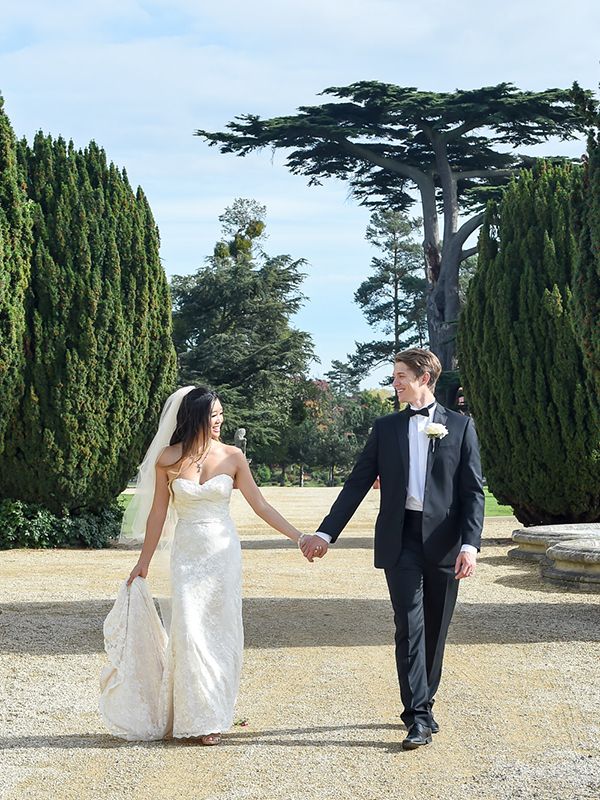 A wedding couple walks together on a scenic path at Stoke Place, beautifully photographed by Abigail's Studio.