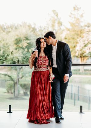 Couple sharing intimate moments in formal attire against an outdoor backdrop with trees and railing.