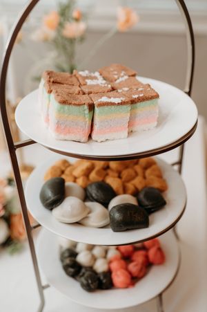 A tiered dessert tray displays an assortment of pink, brown, and white treats on elegant white plates.