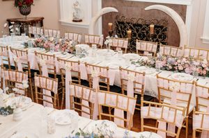 Elegant wedding reception venue with white linens and pink uplighting creating a romantic atmosphere.