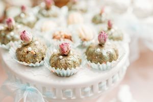 Small pink floral decorated tea cookies arranged on white serving plates with delicate vintage styling.