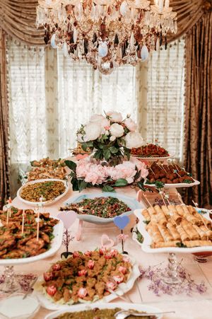 Luxurious wedding reception buffet table with crystal chandeliers and various gourmet dishes on display.
