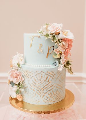 Elegant mint green wedding cake with delicate lace pattern and peach roses on a gold base plate.