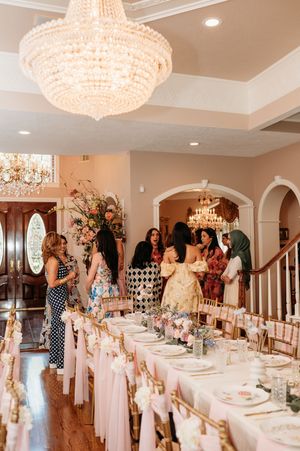 Elegant dining setup in a room with crystal chandeliers and pink table decor for a special celebration event.