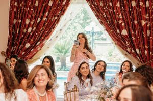 A group of women in formal attire laughing and celebrating together at a festive indoor event.