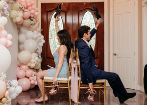 Romantic couple poses in front of pink and white balloon arch decorations at an elegant indoor venue.