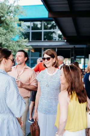People enjoying a casual outdoor social gathering under a covered patio area with teal awning.