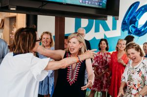 A lively celebration with people laughing and interacting while blue party decorations adorn the background.