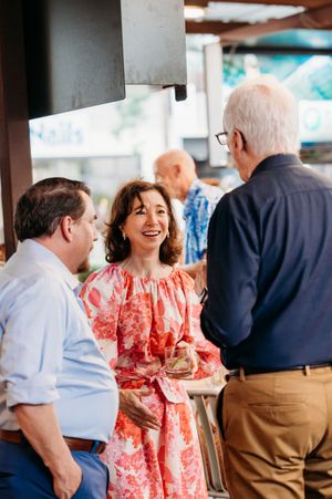 Guests enjoying conversation and laughter at an indoor social gathering wearing red and white attire.
