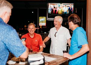 A group of seniors socialize together at a table in what appears to be a restaurant or community gathering space.