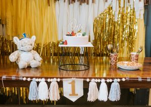 Gold metallic fringe curtains and white party decorations create an elegant backdrop for a festive celebration.