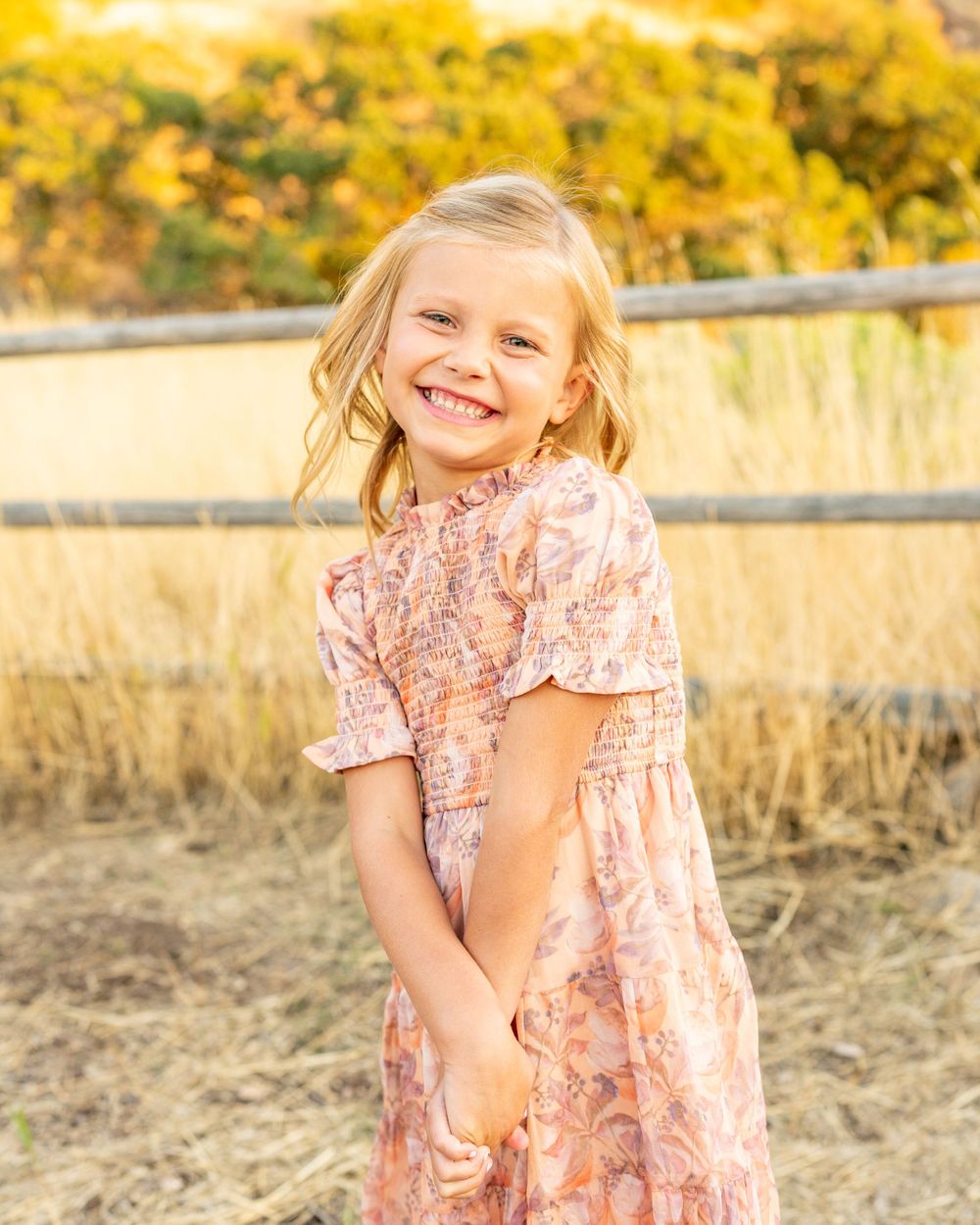 Young girl in pink floral dress poses outdoors in field at golden hour at Hidden Valley Park.