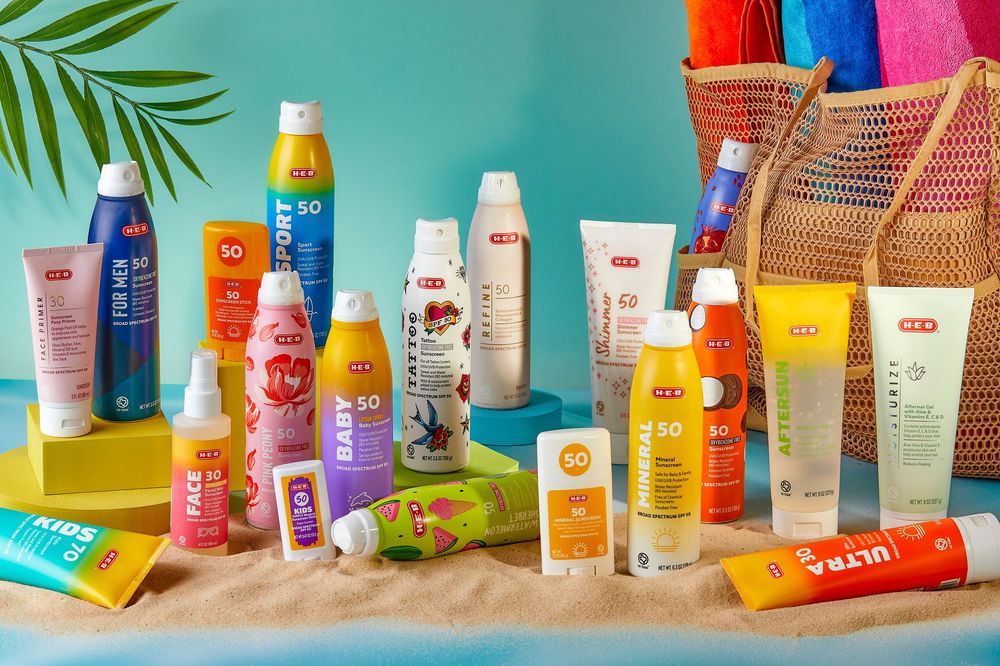 Collection of sunscreen and skincare products displayed with tropical props