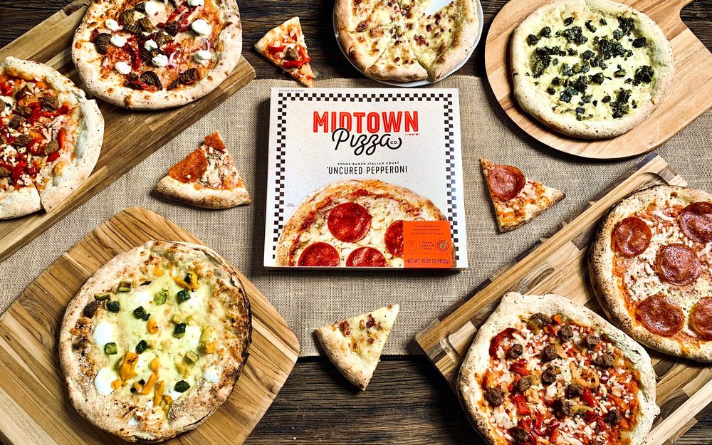 Overhead view of various artisanal pizzas on wooden boards with Midtown restaurant branding.