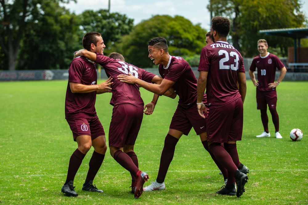 Soccer players in maroon uniforms playing on a green grass field during a match.