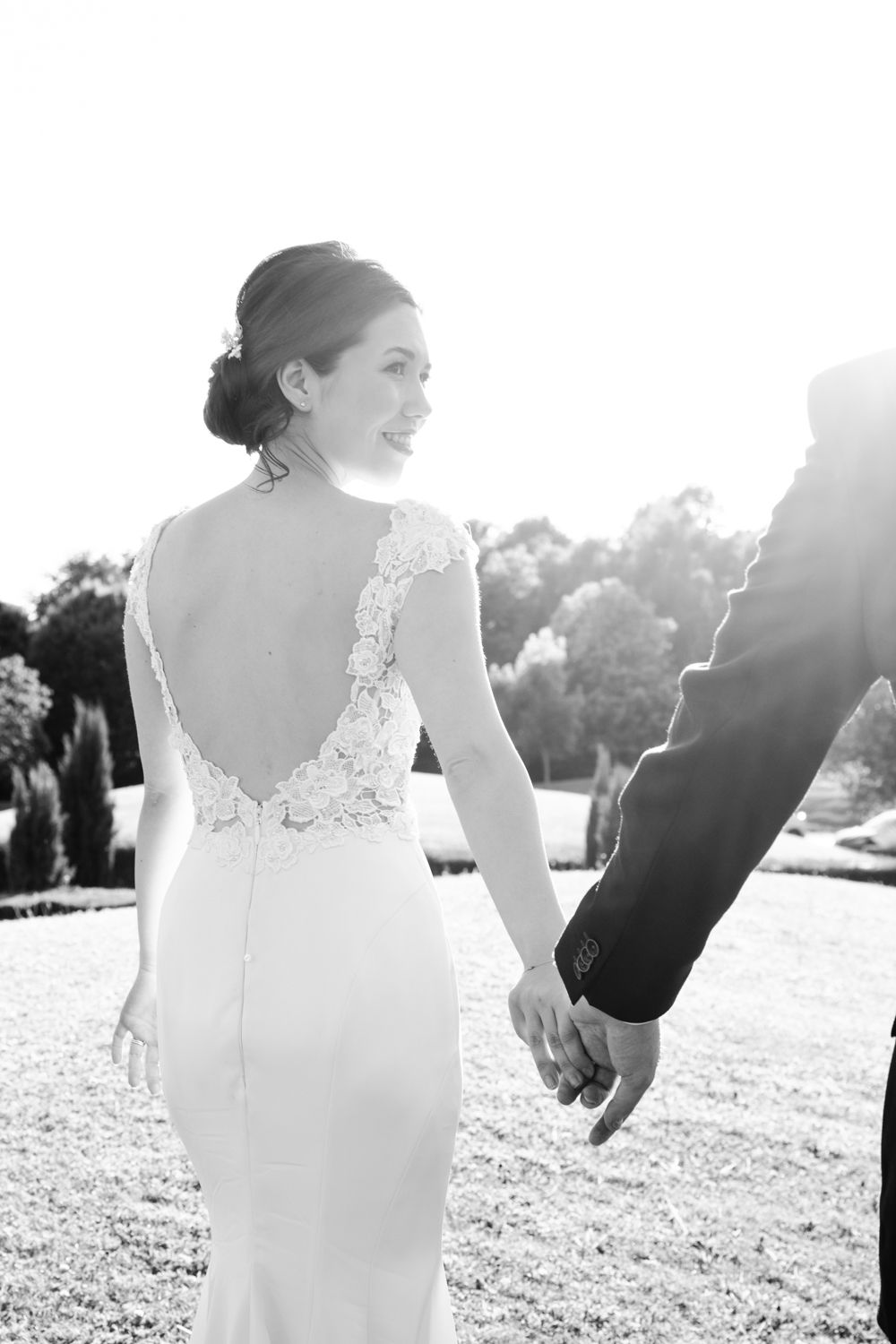 Elegant wedding gown with detailed lace back details captured in outdoor setting.