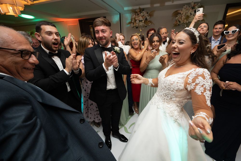Wedding guests celebrate joyfully on the dance floor during a lively reception party.