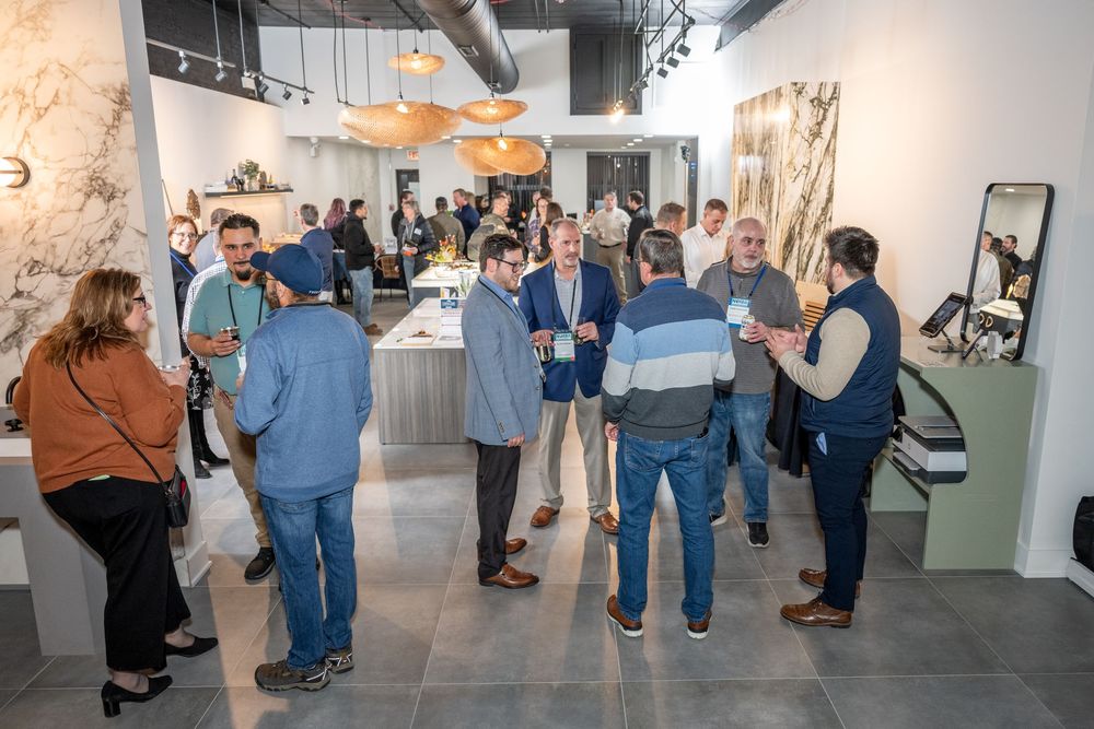 Guests mingle at a modern showroom event featuring stone displays, pendant lighting, and elegant interior design.