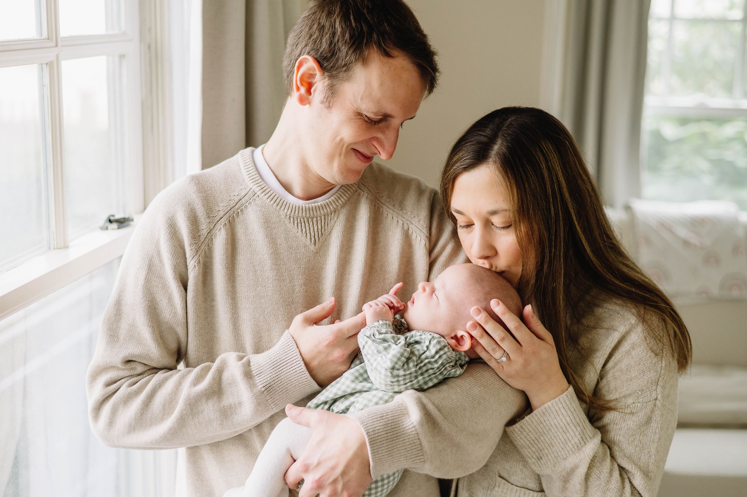 A tender family moment by a bright window with a newborn baby.