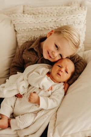 A series of cozy lifestyle photos showing a child resting on white bedding while wearing soft knit clothing.