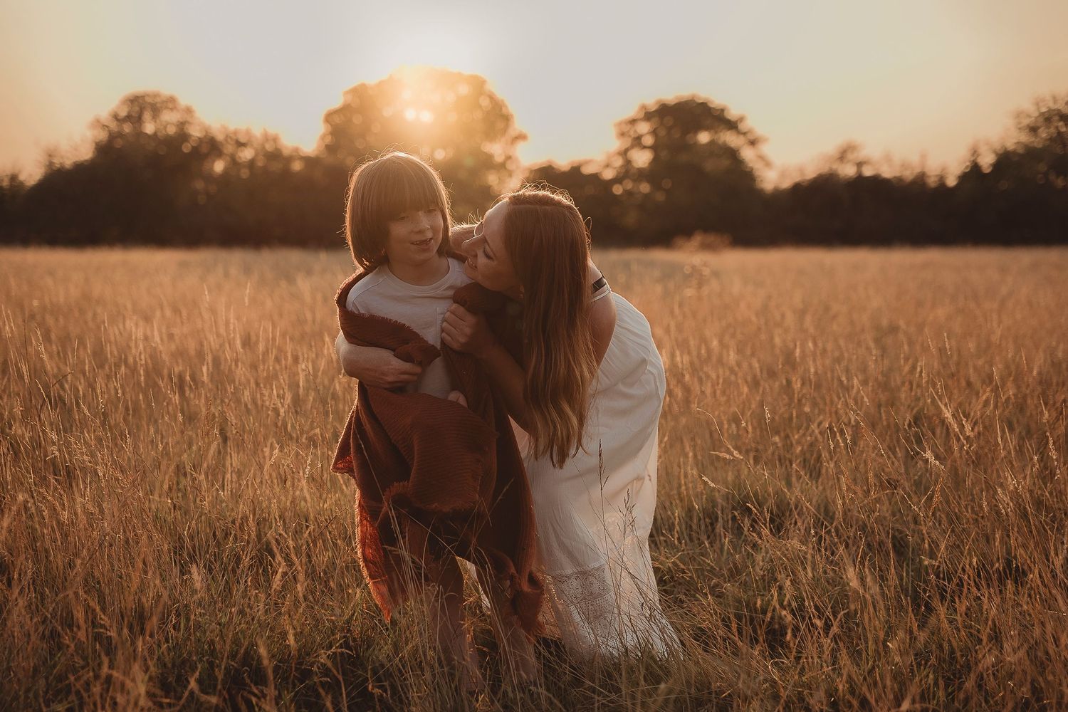 A tender moment between two figures in a golden wheat field at sunset.
