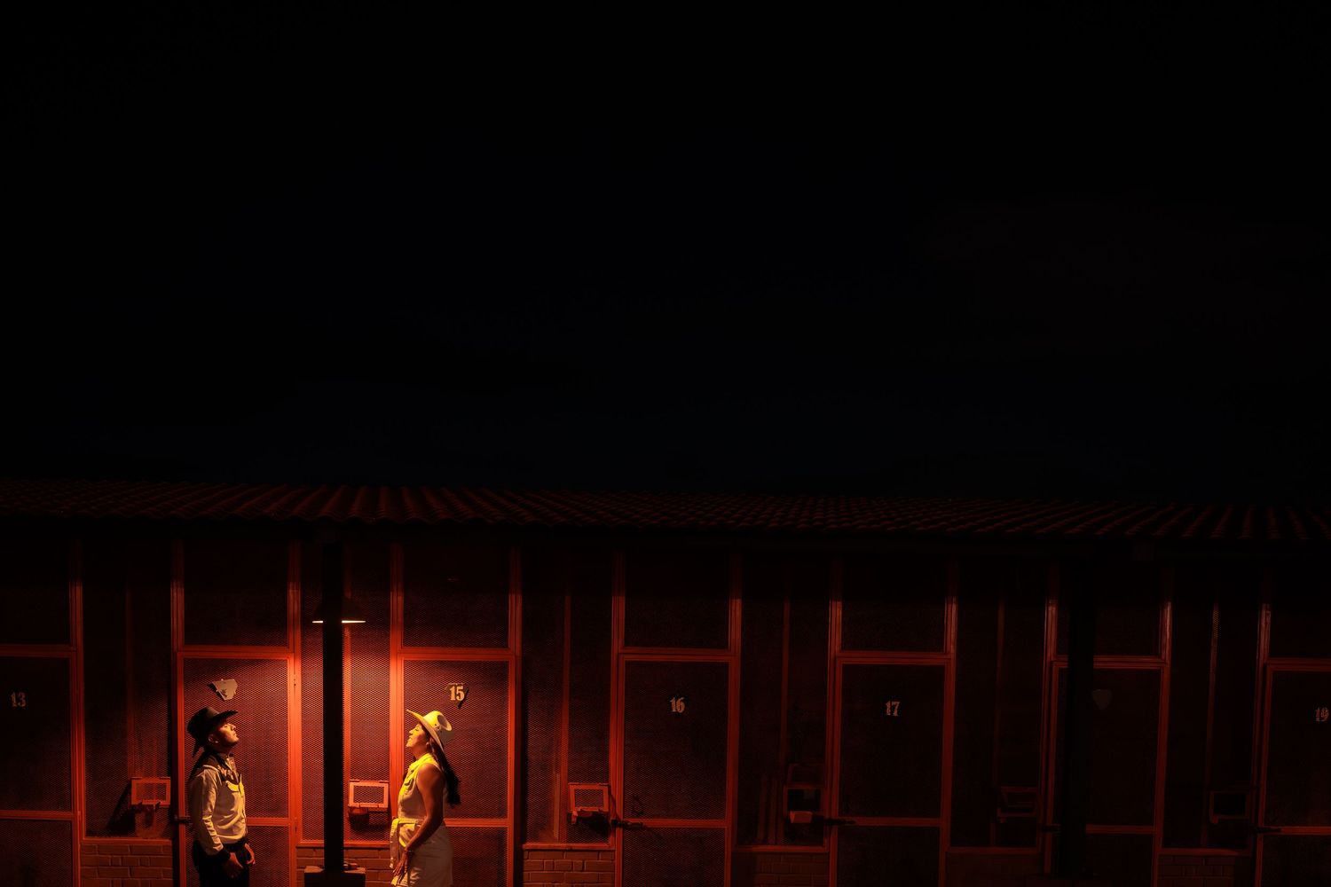 Dark silhouettes against warm red lighting create moody wedding atmosphere.