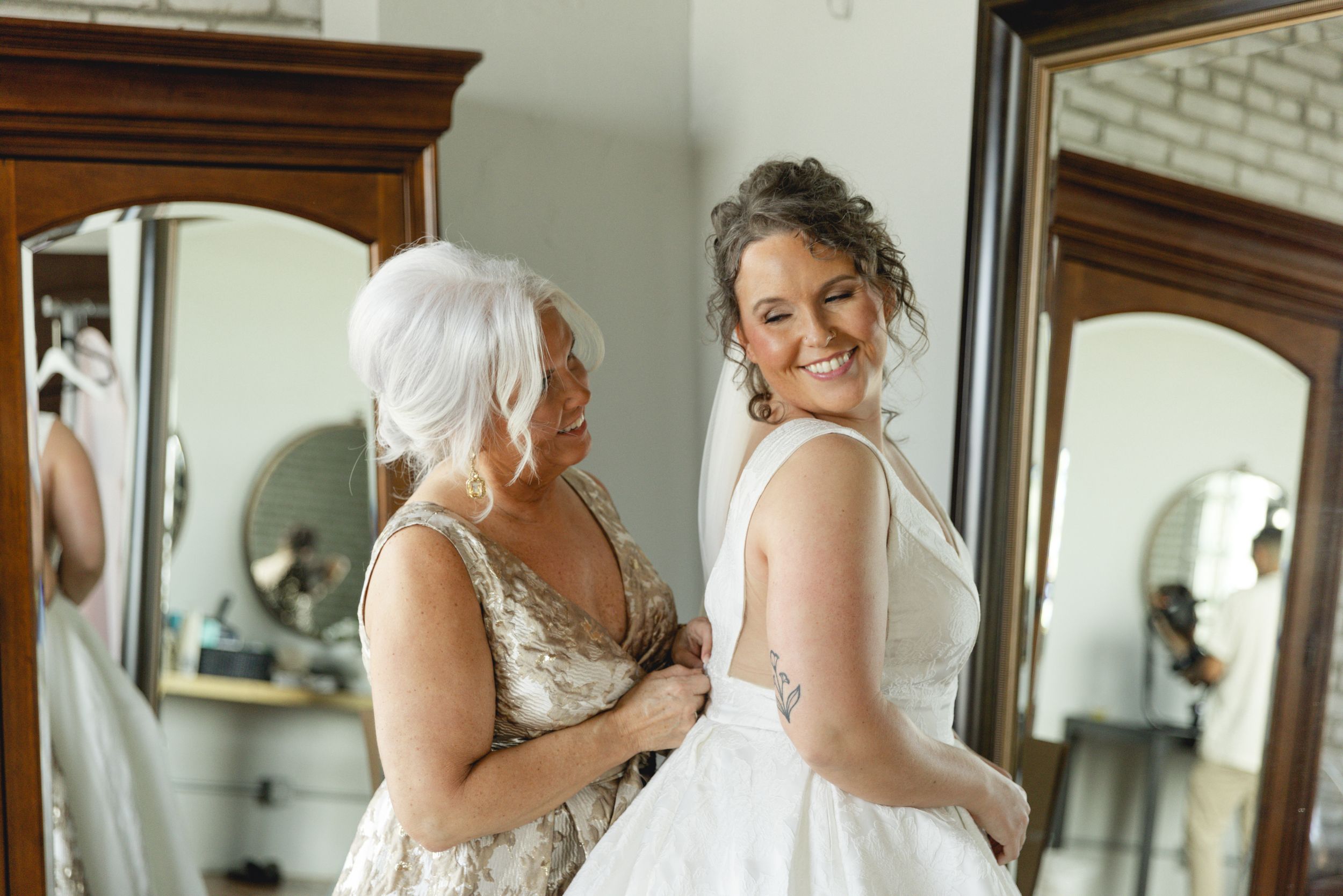 Mom and bride share a sweet candid moment getting dressed for her big wedding day in Des Moines, Iowa.