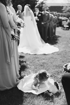 Black and white candid moment of flower girl at ceremony. Documentary style wedding photography in Des Moines, Iowa.