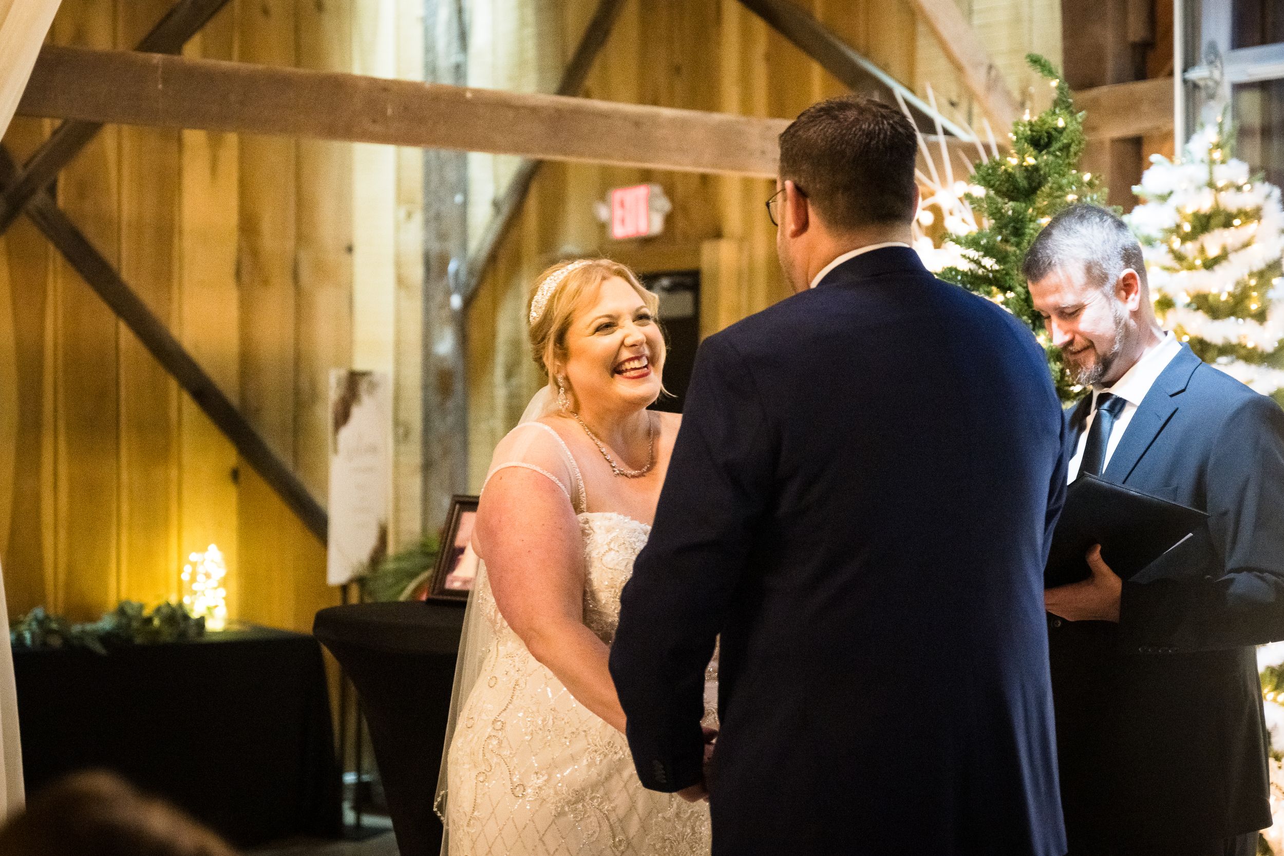 A bride and groom share a romantic dance moment in a rustic wooden barn venue with warm lighting.