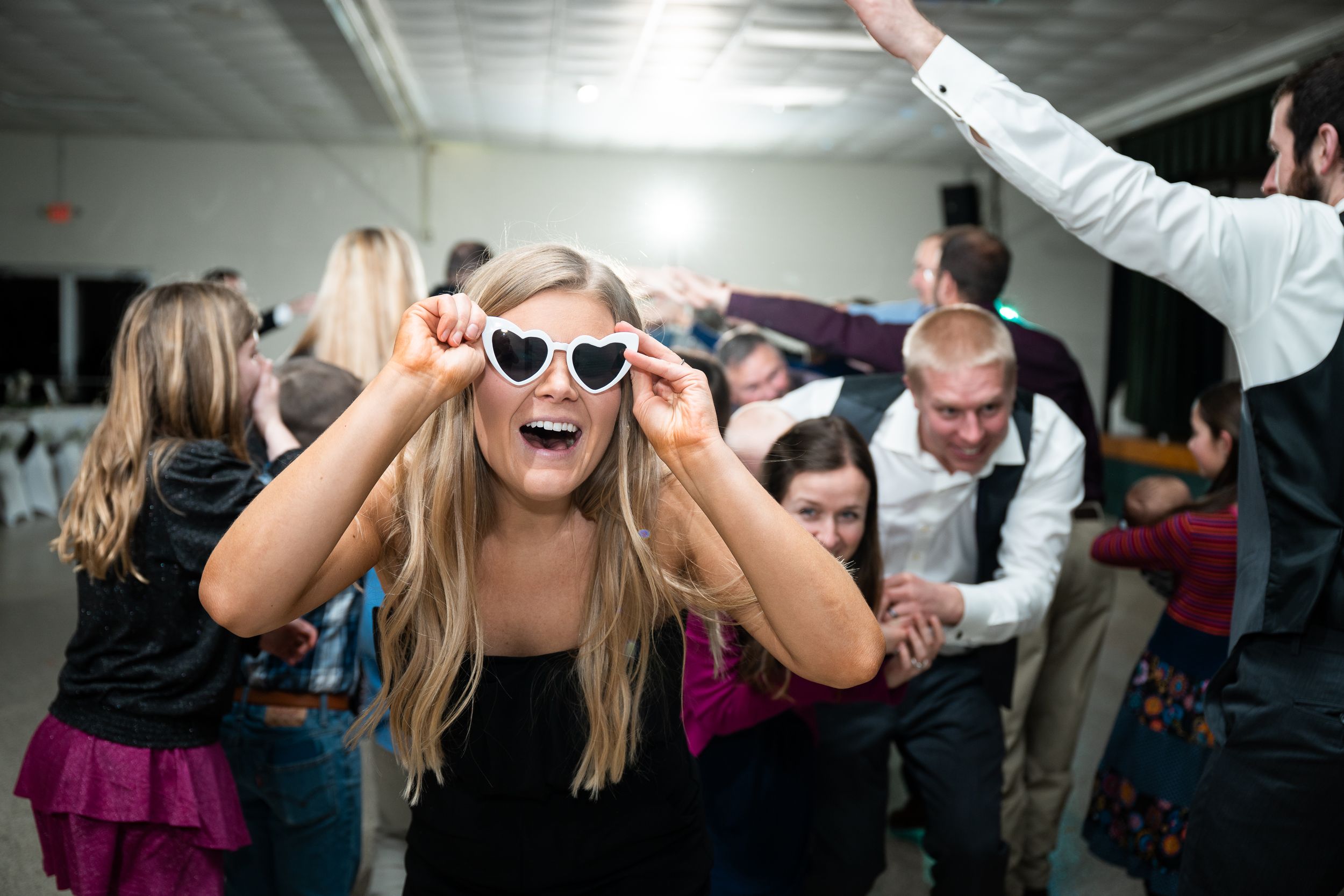 People dancing and laughing together on a dance floor at what appears to be a wedding reception or party.