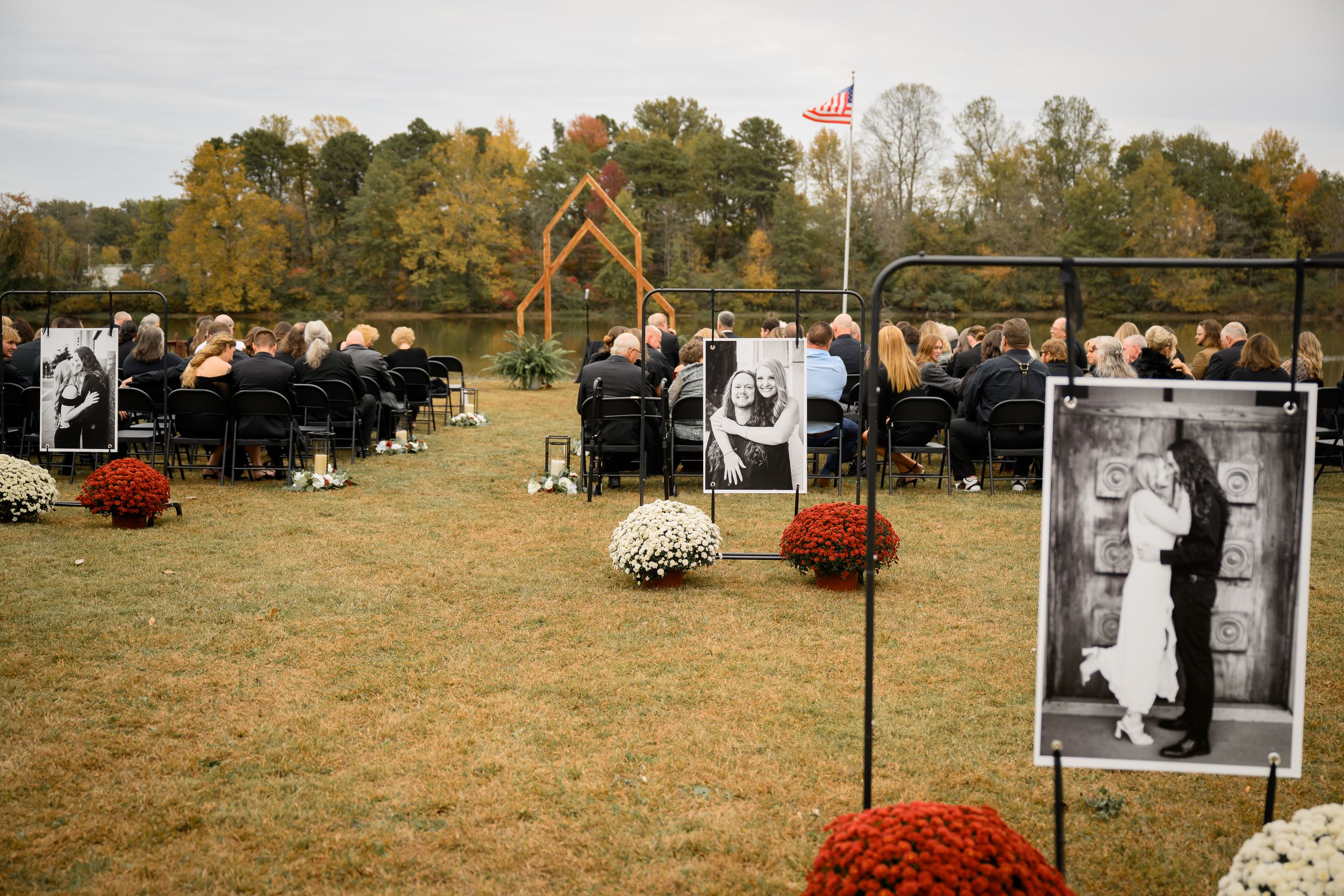 A rustic outdoor wedding ceremony setup with white chairs and orange pumpkin decorations in an autumn field.