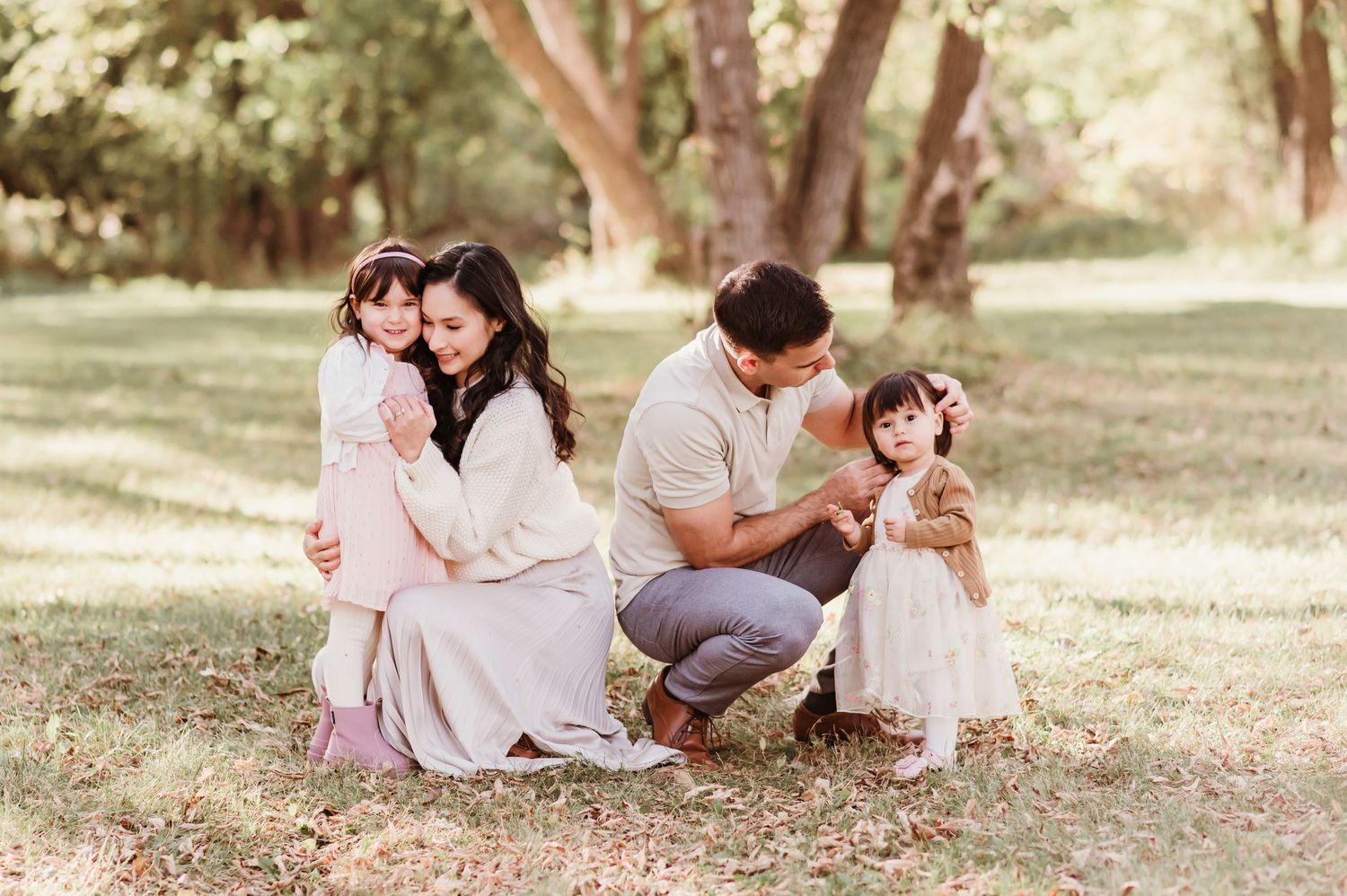 a mom, dad and their children snuggling in the park