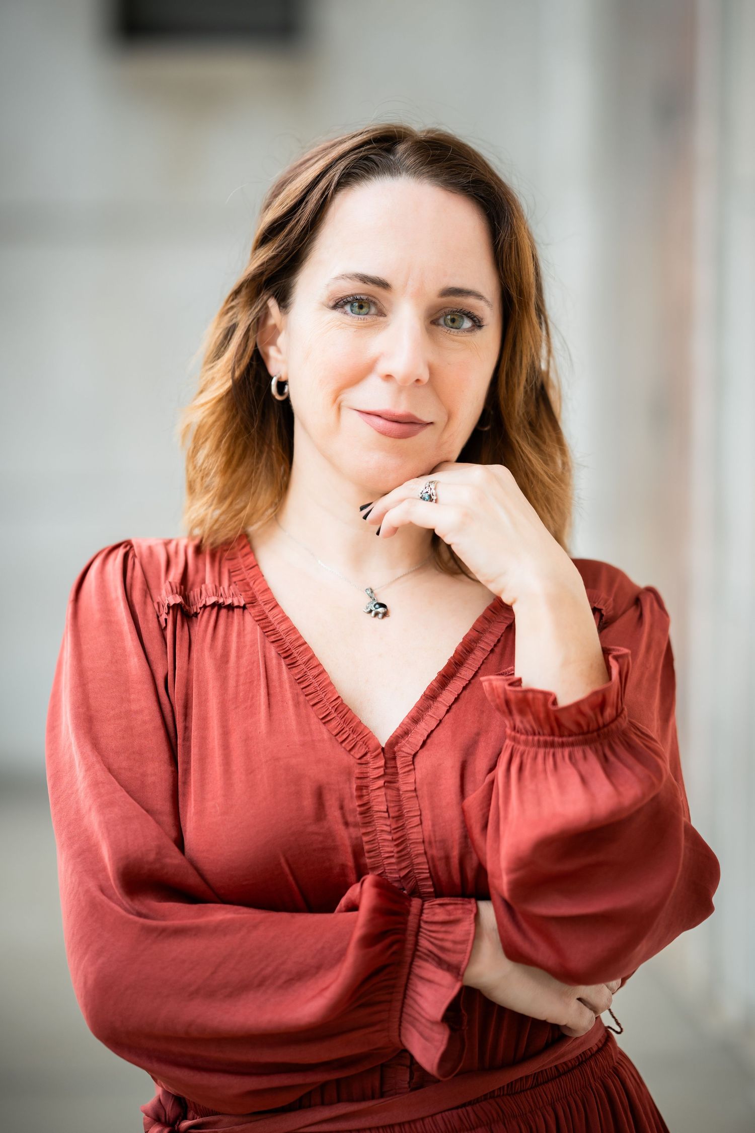 A series of five portraits showing someone in a rust-colored blouse with long sleeves posing against a light background.