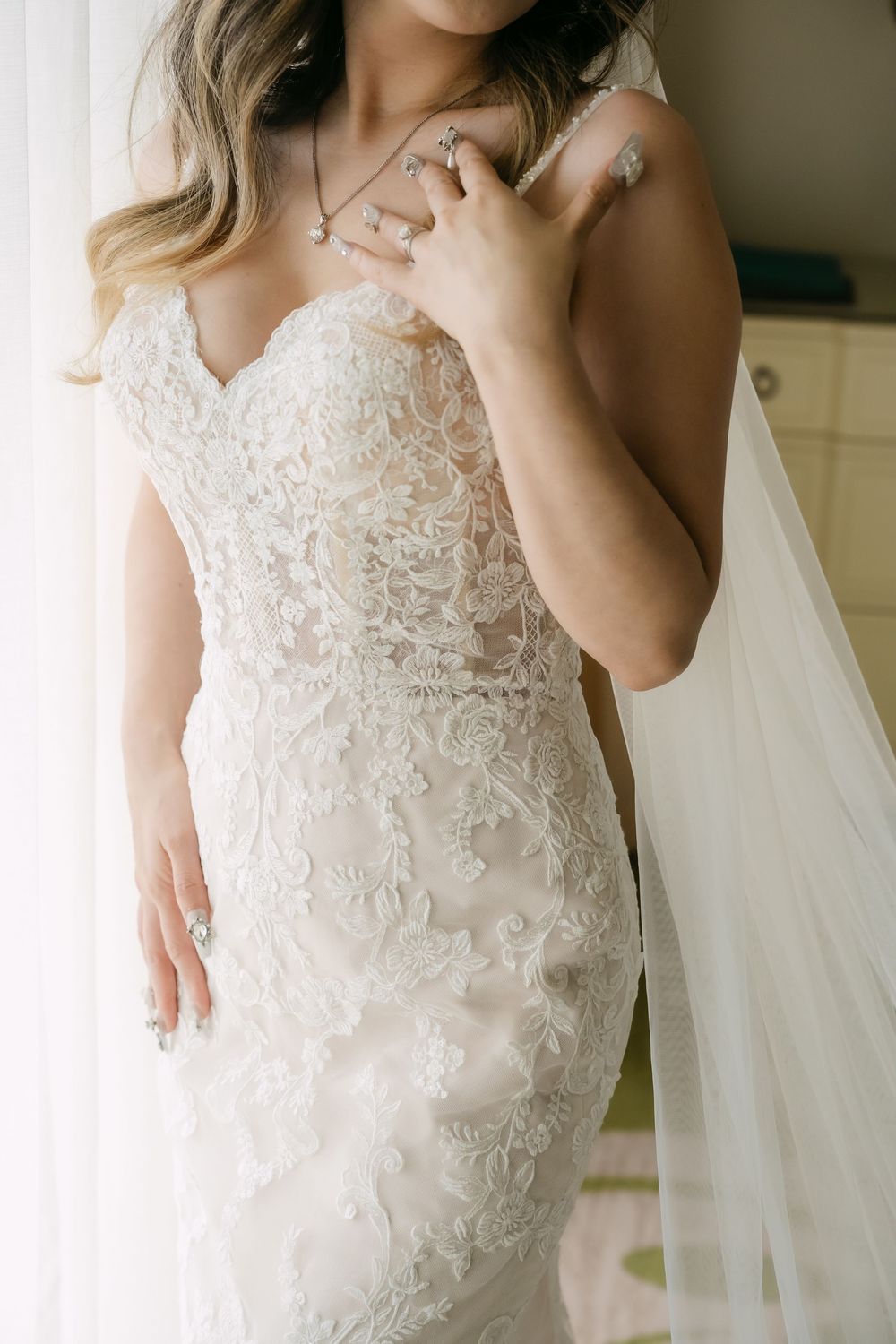 Close-up detail of delicate white lace and beadwork on a wedding dress bodice with sweetheart neckline.