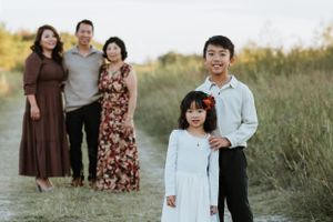 Family portrait session in a grassy field during golden hour.