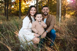 Candid outdoor family portrait session during sunset in a wooded area.