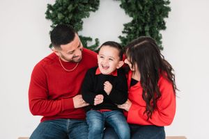 Family in red and black outfits plays and laughs during studio photoshoot.