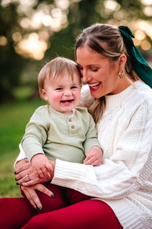 Tender moments captured between parent and child in white knit sweaters against natural backdrop.