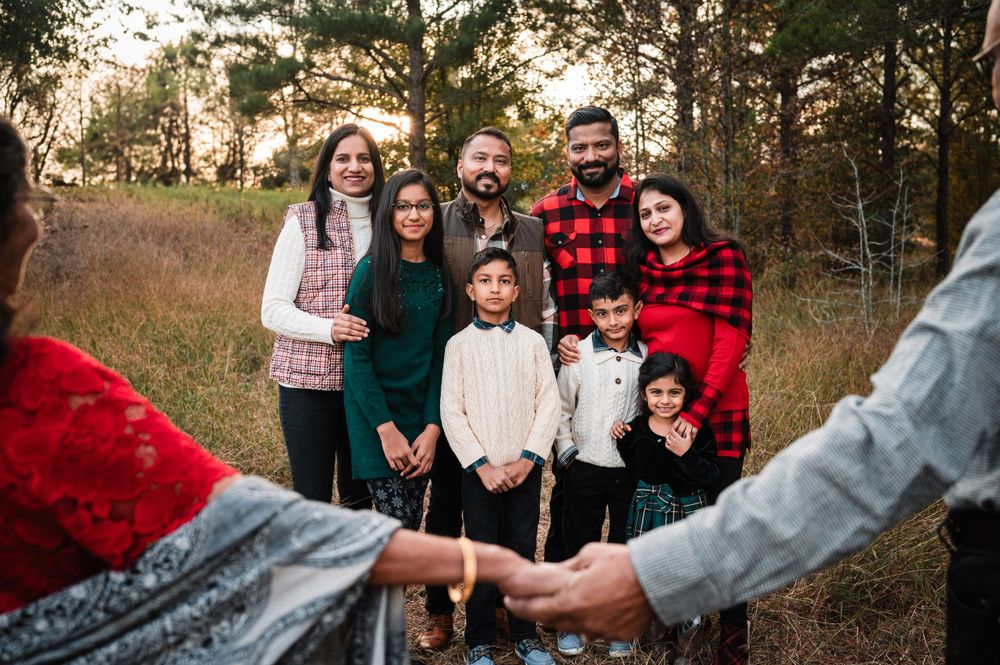 Family wearing coordinated winter outfits poses together in a wooded setting.