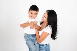 Intimate family photography session capturing loving embraces and genuine smiles in a bright studio setting.